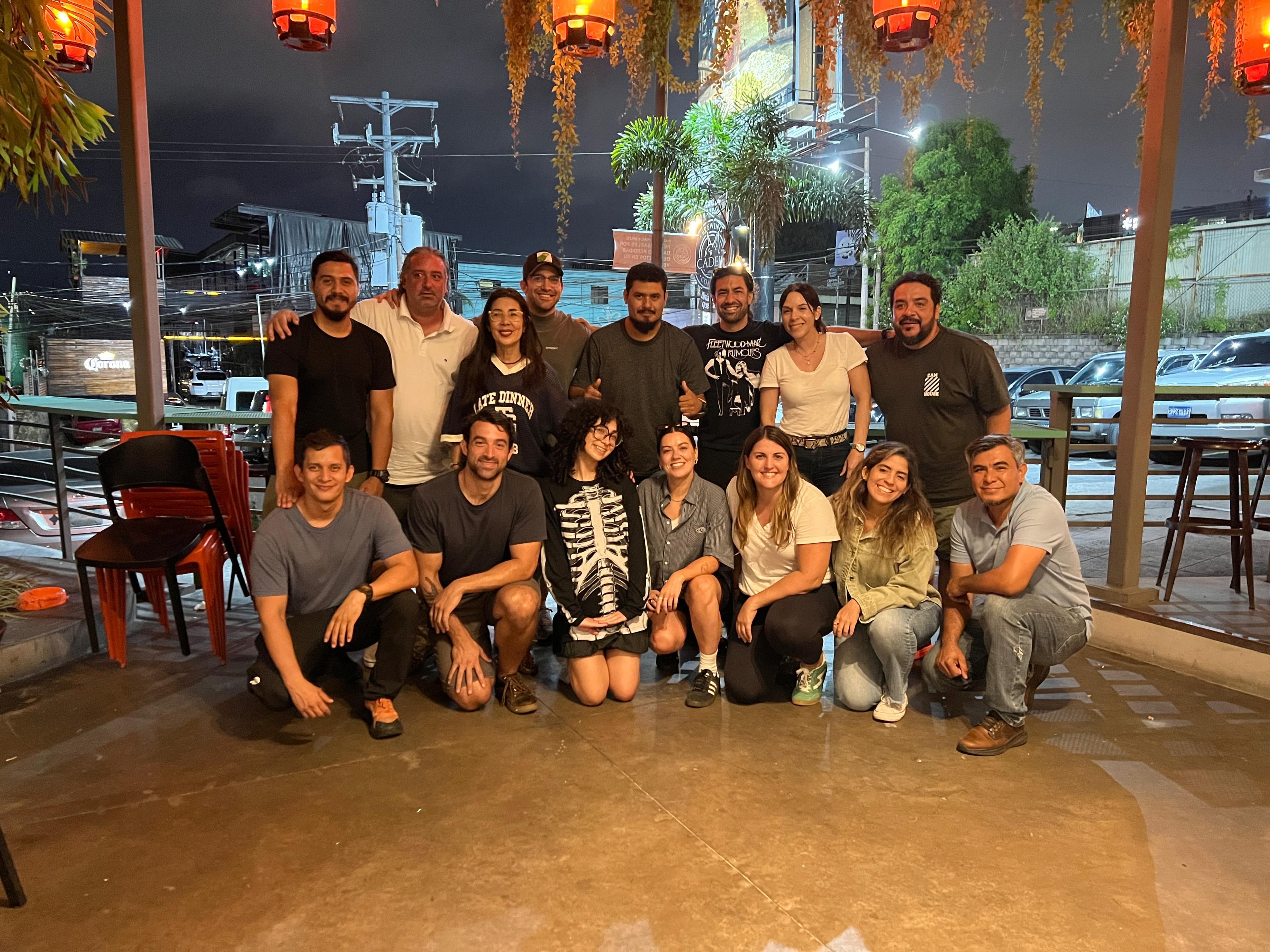 The crew gathers for a group photo at an outdoor restaurant strung with lanterns, celebrating at night after the shoot.